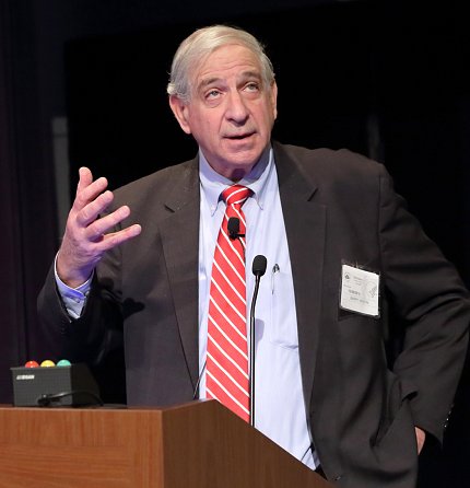 Maron speaks at podium with outstretched hand