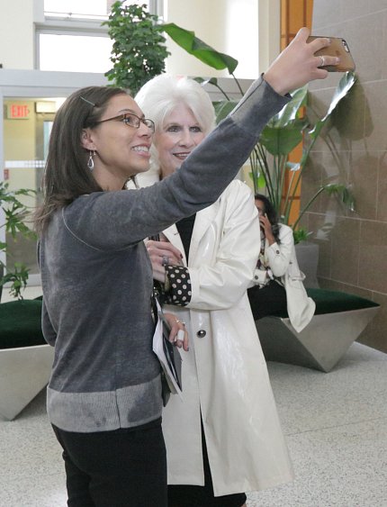 An NIH'er holds up her cell phone to take a photo of herself next to Rehm in the CC atrium.