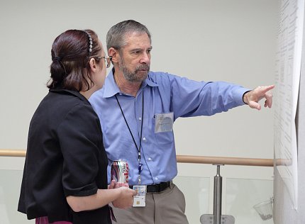 Dr. Lowy points at poster.