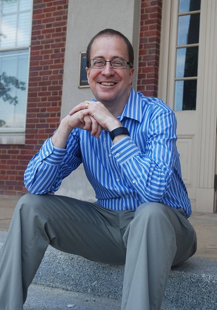 A smiling Eric Dishman sits outside Bldg. 1.