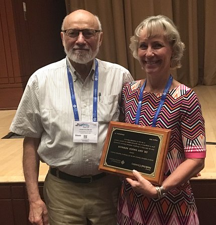 Newman holds award plaque presented by Portoghese.
