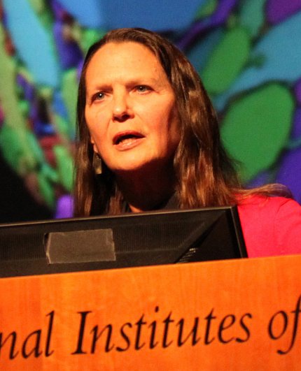 Dr. Hollis Cline speaks at podium in front of colorful slide