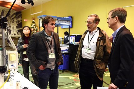 Three men chat a technology fair