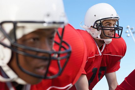 Two football players with red jerseys and white helmets line up to snap the ball