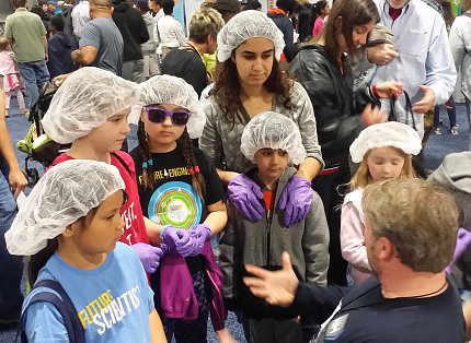 Children listen while volunteer explains mock lab activity in NIH pavilion