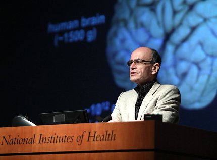 Dr. Südhof at podium in front of slide of human brain
