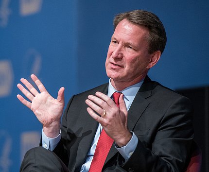 Sharpless gestures with his hands as he speaks to the audience.