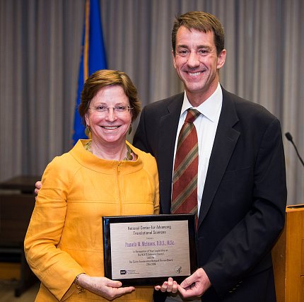 Dr. Christopher Austin presents Dr. Pamela McInnes with a commemorative plaque.