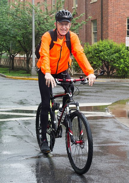 Dr. Francis Collins bicycles onto campus.