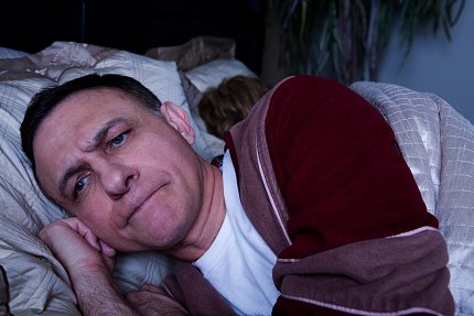 A man lying awake in bed at night