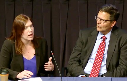 Dr. Frazier Benya speaks at the microphone as Tom Rudin, seated next to her, looks on.