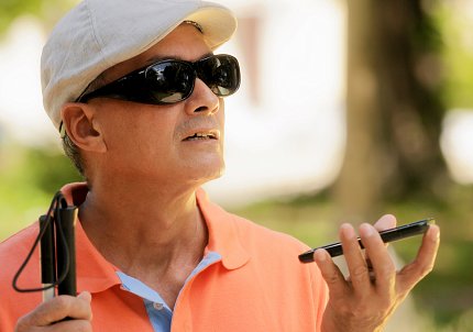 A blind man interacting with a cell phone.