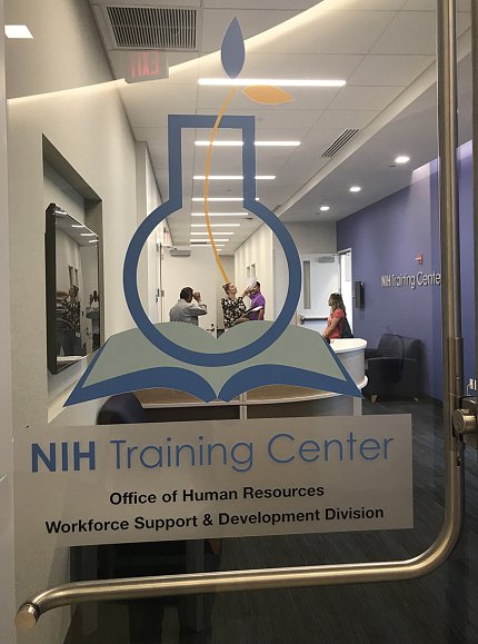 Through the glass door, staff gather in the lounge of the new NIH Trianing Center.