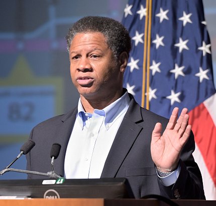 Dr. Robert Winn with raised hand speaks at podium