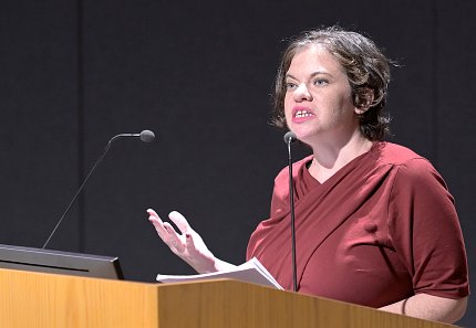 At podium, Posner gestures toward audience.