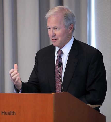 Roth speaks at podium with his hand cupped