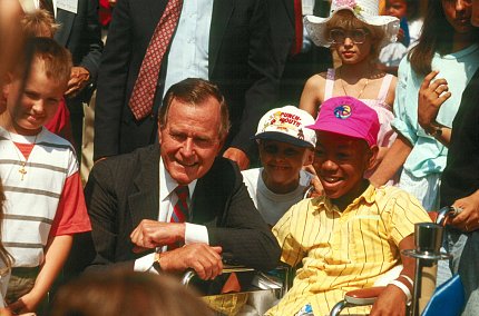 Bush kneels next a child