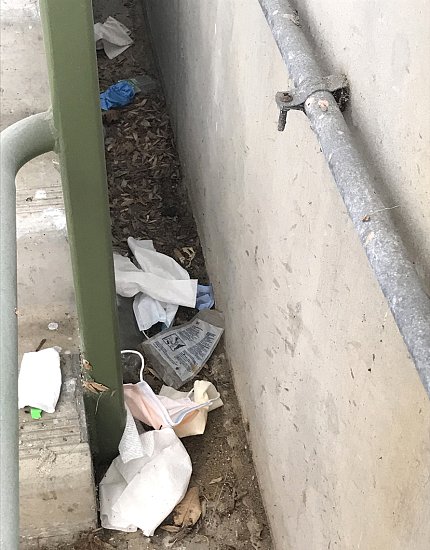 Disposable masks and gloves litter the ground by a campus parking garage.