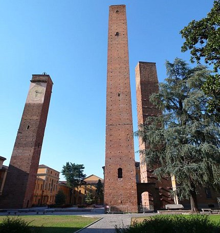 Three brick towers stand against blue sky on the University of Pavia's campus in Italy