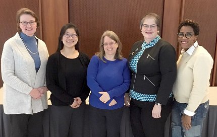 Five women side-by-side smile for camera