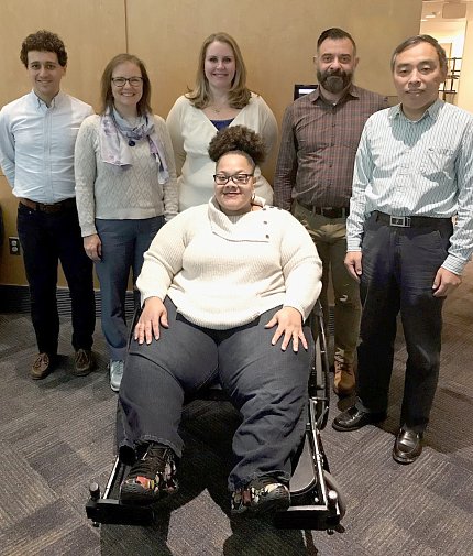 Six people side-by-side smile for camera