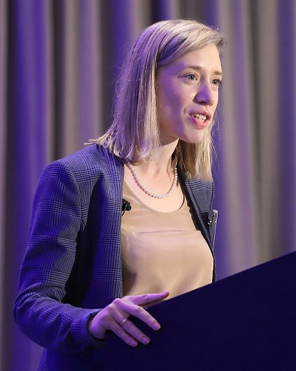 Baker stands at podium in Bethesda Hyatt ballroom.