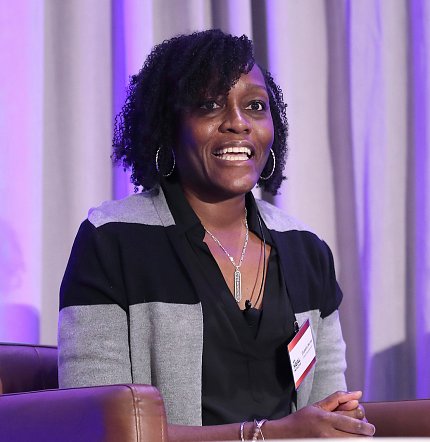 Numa speaks, seated on stage