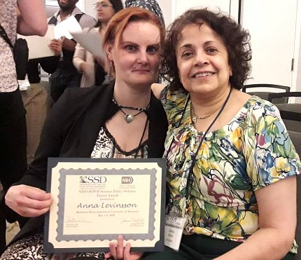 Student shows her mentor an award plaque.