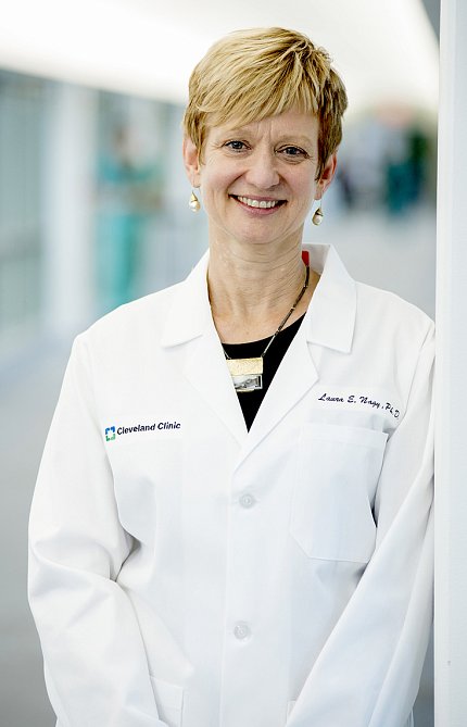 Nagy stands, smiling, in a white lab coat.