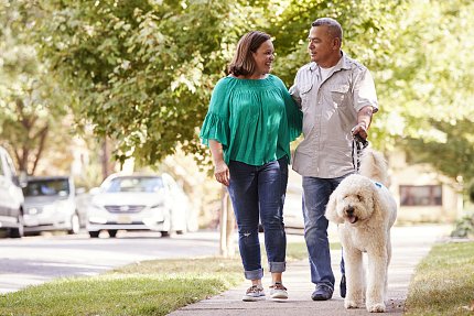 A man and woman walk their dog