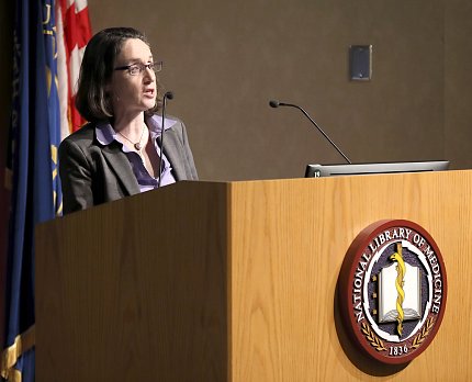 Schultheiss lectures from the NLM podium.