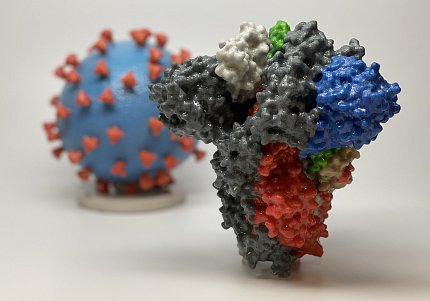 (Foreground) Inverted irregularly shaped pyramid with bumps and crevices; (background) globe with tiny inverted pyramids sticking out from its surface