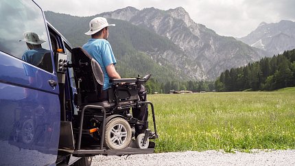 Man on wheelchair views mountains.