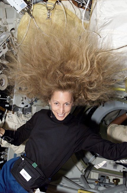 Ivins smiling with hair floating above her face, in zero gravity environment
