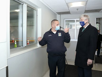 At a window in the facility, Gilroy points out features to Collins.