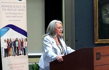 Pinn stands behind a lecturn.