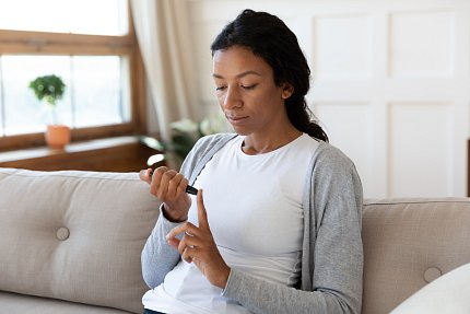 Young woman uses a finger-stick device.