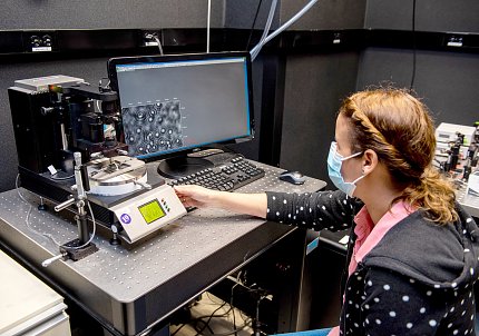 Harami-Papp, in mask, sits at a computer monitor and adjusts parts of a machine