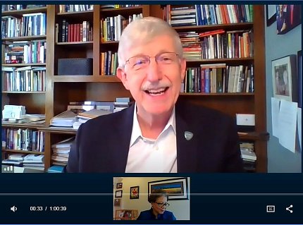 A smiling Dr. Collins speaks on video surrounded by books in his home office.