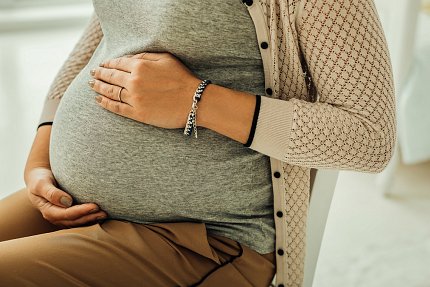 Pregnant woman torso with hand on baby bump