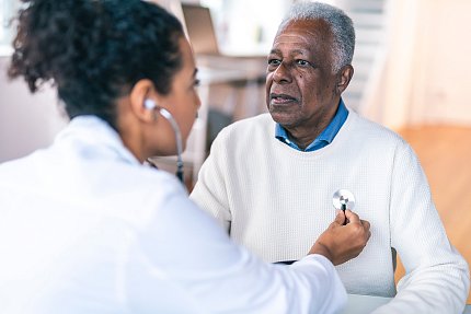 A doctor holds a stethoscope up to an older adult's heart