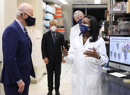 In lab, Corbett briefs President Biden as others look on.