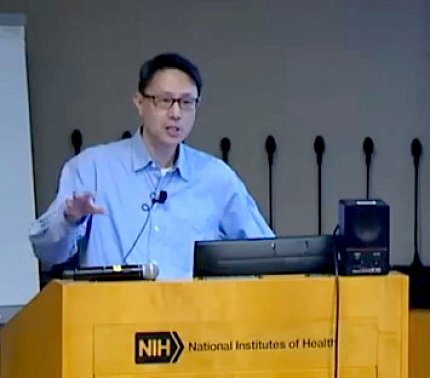 Chow speaks from a podium branded with the NIH logo 