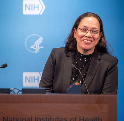 A smiling Quiroz stands at podium in Lipsett Amphitheater