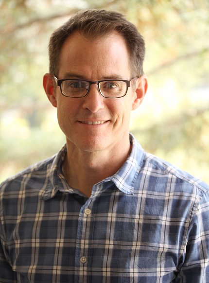 Head shot of Dr. Justin Sonnenburg in plaid shirt, glasses