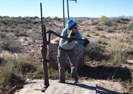 Woman at outdoor water pump with handle