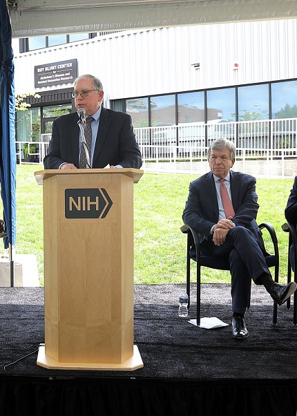 Tabak speaks and Blunt looks on