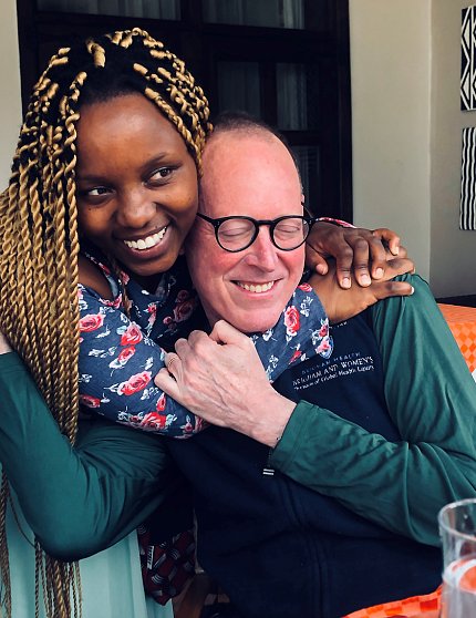 Humure, smiling, hugs Dr. Farmer, who - eyes closed and smiling - hugs her back.