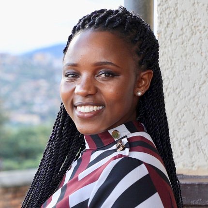 Head shot of Humure, smiling, leaning against wall outside