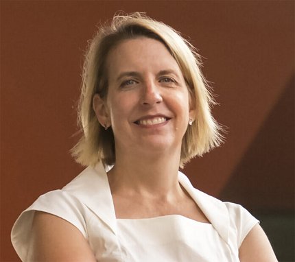A smiling McGraw in white shirt with brown background